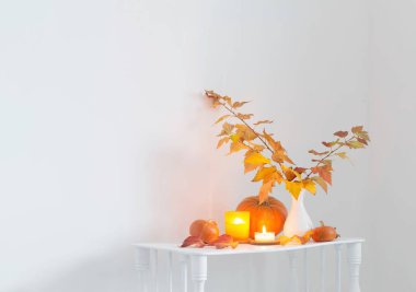 Beyaz vazodaki sonbahar buketi ahşap rafta, beyaz iç kısımda.