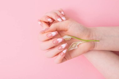 Pembe arka planda çiçekli güzel uzun tırnaklı kadın elleri