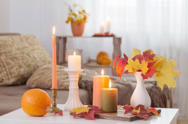 Evdeki beyaz masada sonbahar dekoru ile mum yakmak.