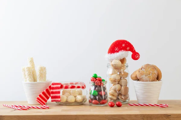 christmas candies and cookies  in jars on wooden shelf on white background