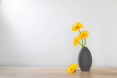 Ahşap raftaki vazoda sarı gerbera