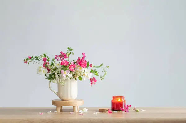 summer flowers and burning candles   on light  background