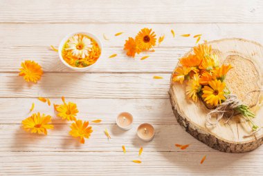 Beyaz ahşap arka planda yanan mumlar ile Calendula tıbbi çiçekler