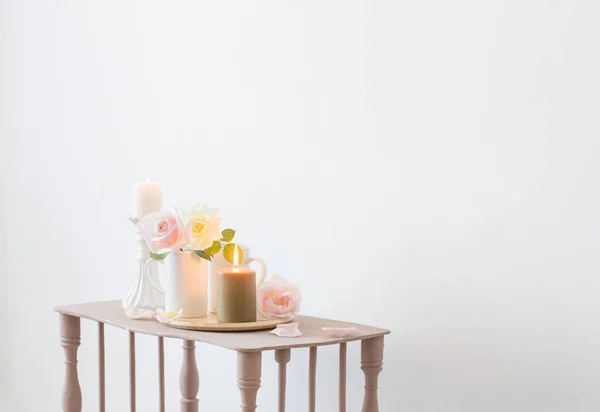 beautiful roses and burning candles on white background