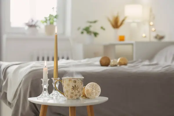 Beyaz Yatak Odasındaki Küçük Masada Noel Topları Olan Bir Fincan — Stok fotoğraf