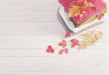 Sonbahar yapraklı kazak yığını beyaz ahşap masada.