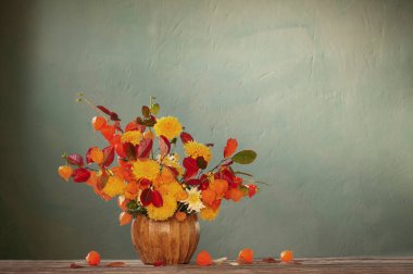 Koyu renk duvardaki ahşap masada güzel bir sonbahar buketi