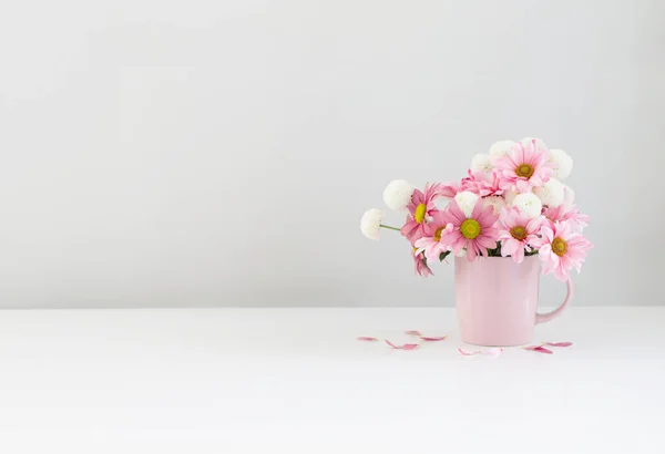 white and pink  chrysanthemums in pink cup on white background