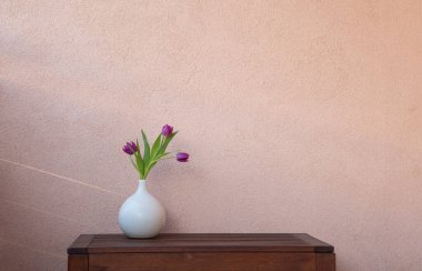 Arkadaki duvarda mor laleler var.