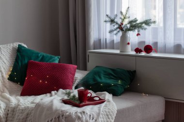 Kanepede köknar dalları olan ahşap tepside kırmızı bir fincan çay.