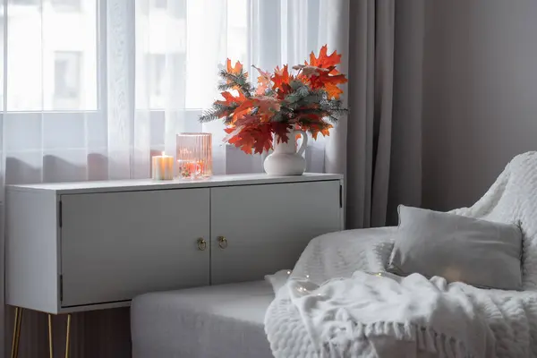 white modern room with autumn bouquet and pillows on sofa
