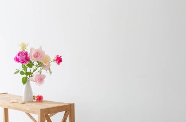 Beyaz arkaplanda beyaz seramik vazoda pembe ve beyaz güller