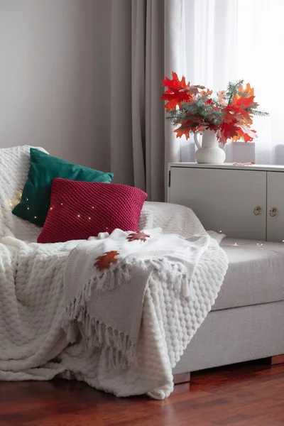white modern room with autumn bouquet and pillows on sofa