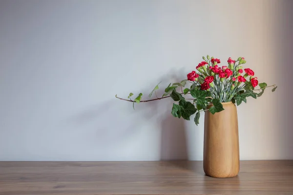 red carnations  in modern vases on background gray wall