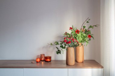 Arka plandaki gri duvarda modern vazolarda kırmızı karanfiller ve laleler