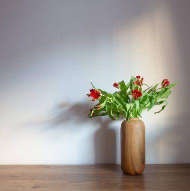 Arkadaki gri duvarda modern vazolarda kırmızı laleler