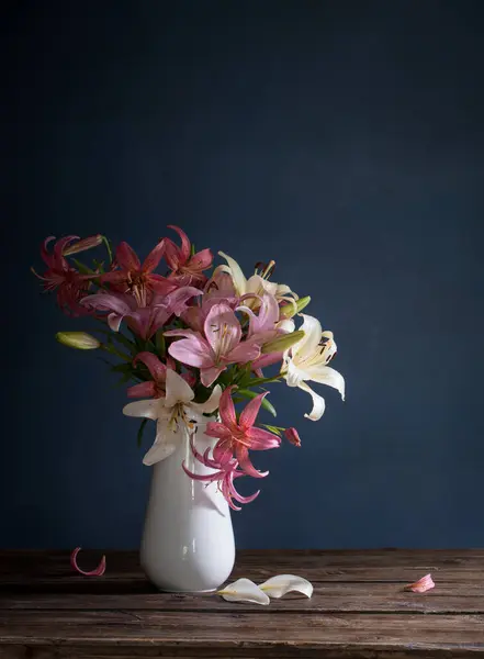 bouquet of lily flowers in vase on dark background