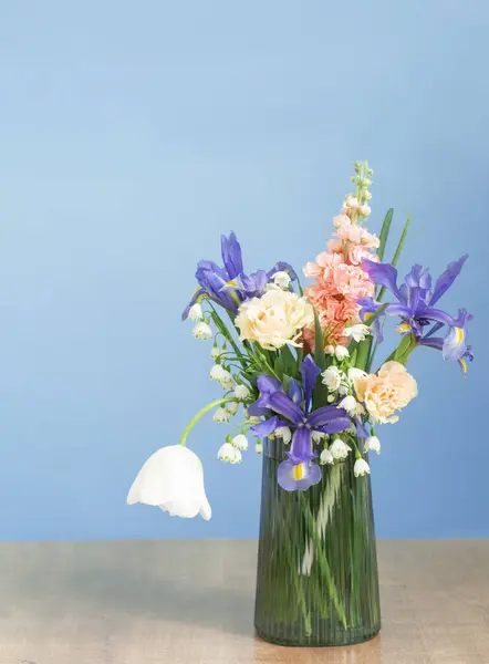 spring flowers in glass vase on blue background