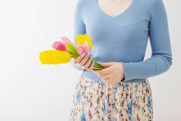 Beyaz arka planda bir buket lale olan genç bir kız.