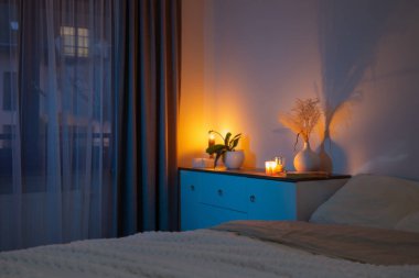 Geceleri yatak odasındaki vazoda çiçeklerle mum yakmak.