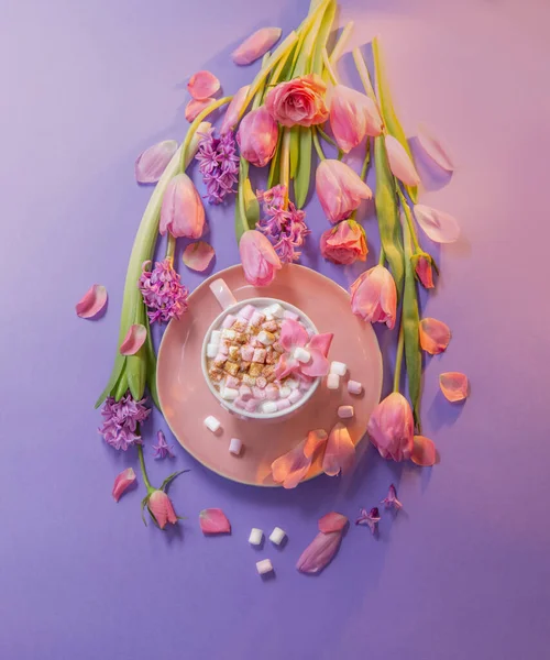 pink cup of cocoa with marshmallow  with spring flowers on purple background
