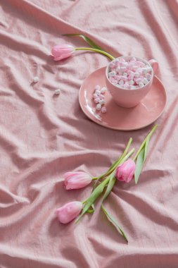 Lalelerle pembe arkaplan ve fincanda şekerlemeler