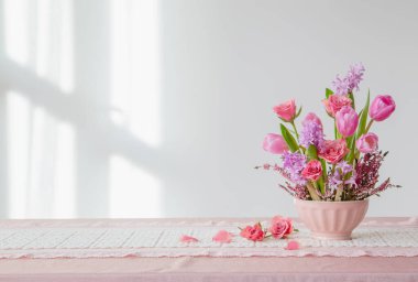 Arkadaki beyaz duvarda vazoda pembe çiçekler