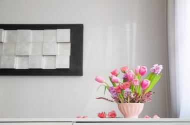 Arkadaki beyaz duvarda vazoda pembe çiçekler