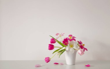 Beyaz vazoda beyaz ve pembe laleler arka plan duvarında
