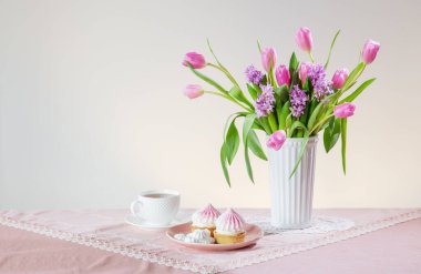 Bir fincan çay ve açık renkli bahar çiçekli kekler.