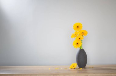 Ahşap raftaki vazoda sarı gerbera