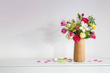 Vazodaki güzel çiçekler arkaplandaki rafta beyaz duvarda