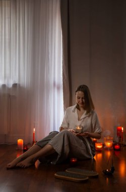 Evde çivi tahtası ve yanan mumlarla genç bir kadın.