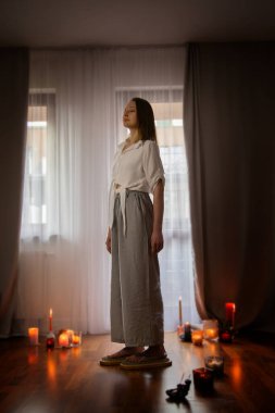 İçerideki genç kadın elinde mumlarla çivi tahtasında duruyor.