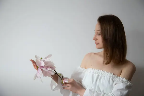 Młoda Elegancka Kobieta Białej Sukience Wiosennymi Kwiatami Wazonach Szarym Tle Obrazek Stockowy