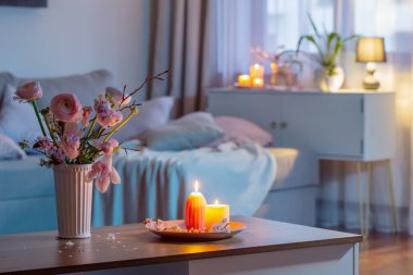 Bahar çiçekleri ve yanan mumlarla dolu bir ev.