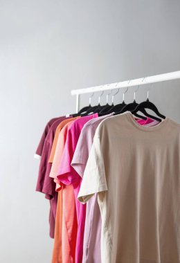row of t-shirts on a hanger against a background of a white wall hanger clipart