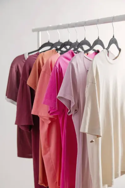 stock image row of t-shirts on a hanger against a background of a white wall hanger