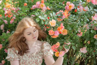 Parkta gülleri olan güzel bir kadın.