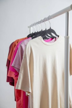 row of t-shirts on a hanger against a background of a white wall hanger clipart