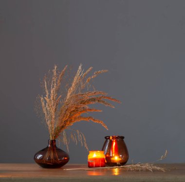 Kurumuş çiçekler ve yanan mumlar arka plandaki karanlık duvarda.