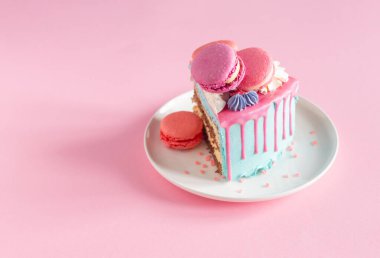 Pembe ve mavi desenli bir parça kek beyaz tabakta pembe arka planda