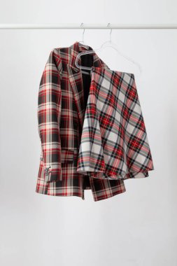 Kadın ceketi ve etek beyaz arka plandaki askıda kareli desenli.