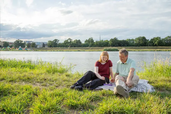 stock image father and daughter sitting on the grass and eating ice cream