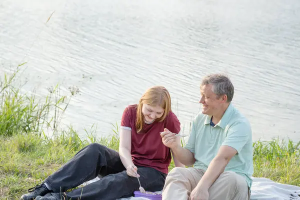 stock image father and daughter sitting on the grass and eating ice cream