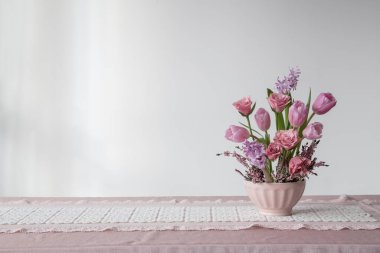 Arkadaki beyaz duvarda vazoda pembe çiçekler