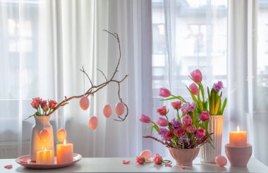 Çiçekli, yumurtalı, yanan mumlu paskalya evi dekoru.