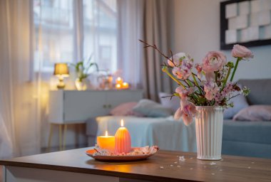 Bahar çiçekleri ve yanan mumlarla dolu bir ev.