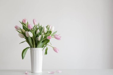 Beyaz vazoda beyaz ve pembe laleler arka plan duvarında