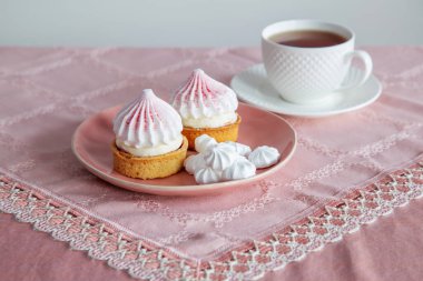 beyaz ve pembe kekler ve bir fincan çay klasik masa örtüsü üzerinde
